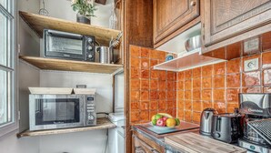 A compact kitchen with wooden shelves, a microwave, a toaster, and a coffee maker. - Cozy Studio in The Heart of Latin Quarter (Paris)