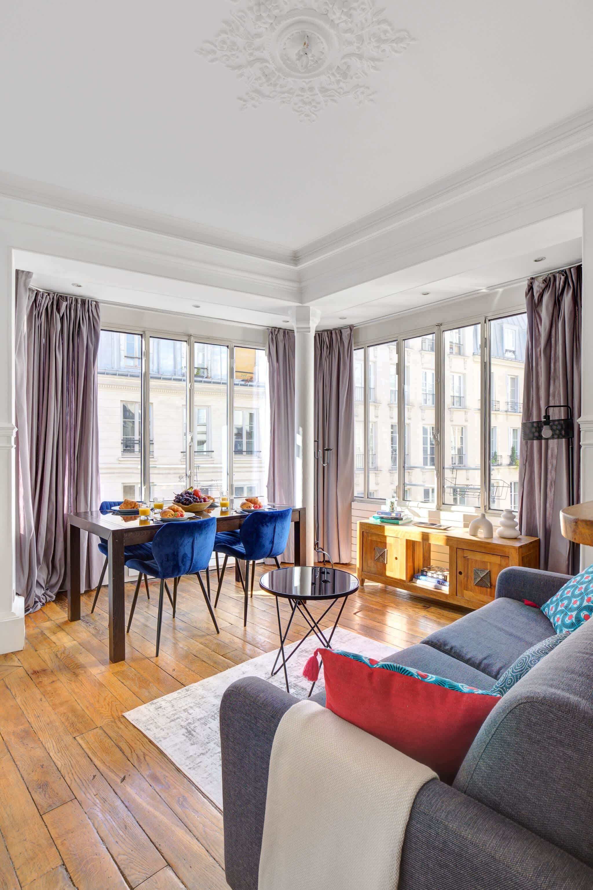 Un salon moderne avec un coin repas, de grandes fenêtres et une vue sur les immebles.