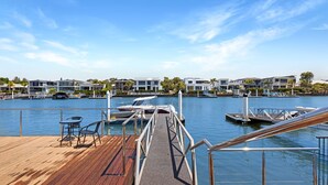 A marina with boats docked, a wooden deck, and modern buildings in the background.
