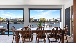 A dining area with a table and chairs, large windows with a marina view, and a modern building in the background.