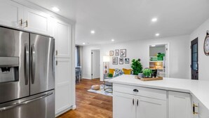 A modern kitchen with white cabinetry, stainless steel appliances, and a central island. - Hidden Renovated Garden Cottage Near Costco, I99 (Shoreline)