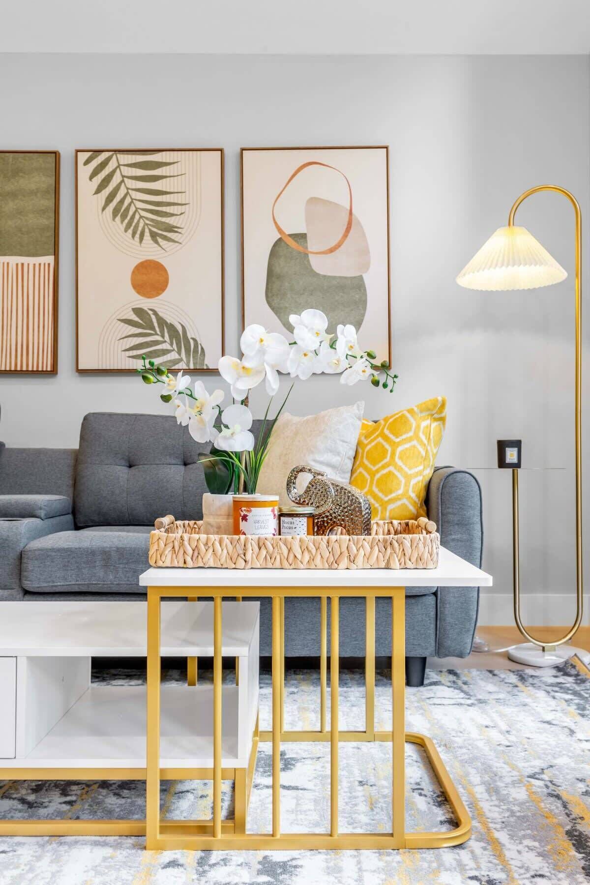 A modern living room with a grey sofa, a white coffee table with a woven tray, and a floor lamp.