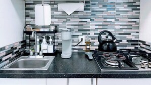 A modern kitchen with a black countertop, a coffee maker, a kettle, and a sink.
