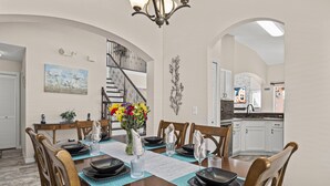 A dining room with a wooden table set for six, a chandelier, and a staircase leading to another level. - ⭐⭐5 Bed, 4 Bath Property | SOUTH Facing Pool | Gated Resort | Mins to Disney ⭐⭐ (Davenport)