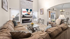 A living room with a fireplace, a large TV, and a cozy seating area. - ⭐⭐5 Bed, 4 Bath Property | SOUTH Facing Pool | Gated Resort | Mins to Disney ⭐⭐ (Davenport)