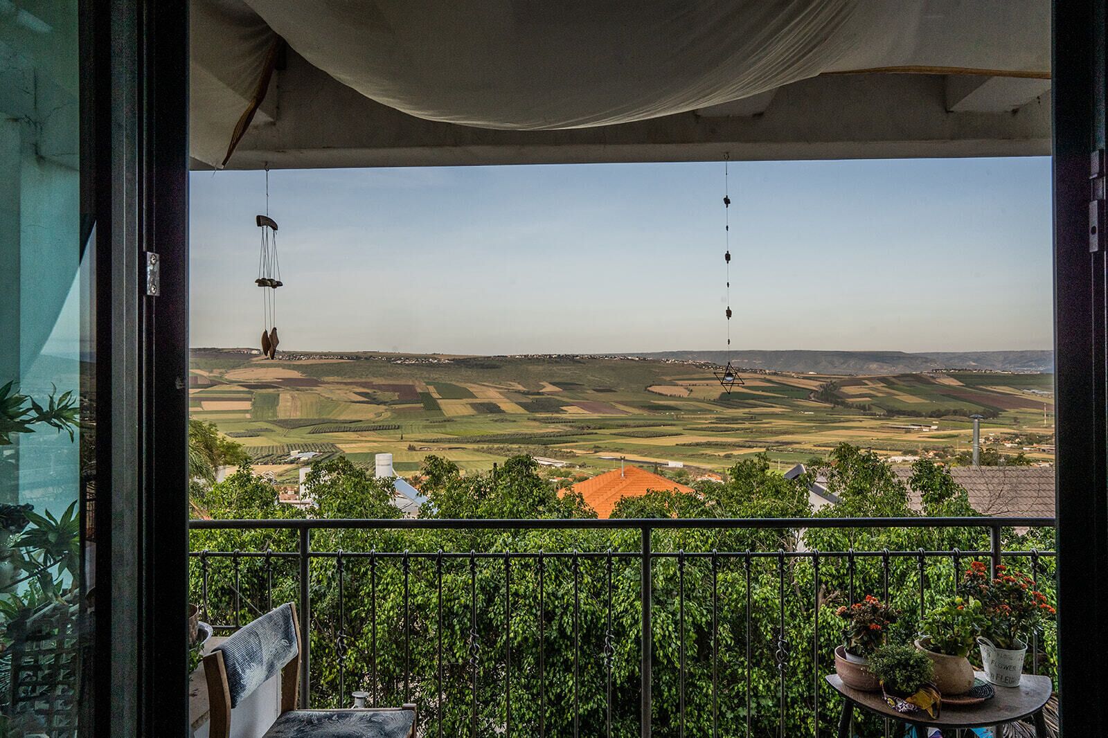 Un balcón con vistas a un paisaje rural, que incluye campos y edificios lejanos.