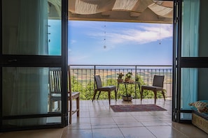 An open balcony with a view of a green landscape, two chairs, a small table with potted plants, and a hanging light fixture. - Loveneel Sea Galilee Retreat by SeaNRent (Yavne'el)