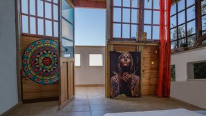 A spacious room with large windows, a wooden door, and a colorful circular artwork on the wall. - Loveneel Sea Galilee Retreat by SeaNRent (Yavne'el)