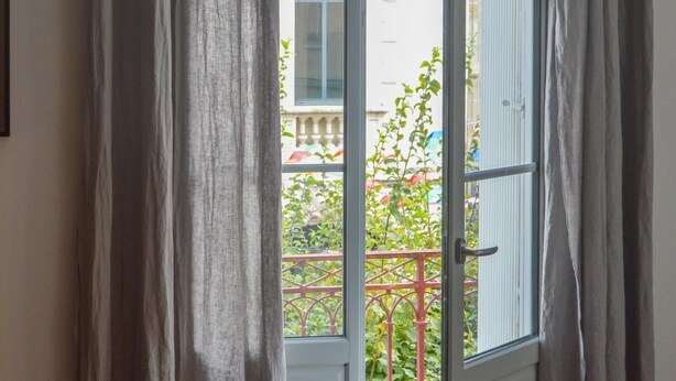 Puerta abierta con vistas a un balcón y un edificio al fondo.
