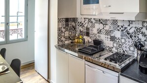 Una cocina moderna con azulejos decorativos en la pared, horno empotrado y comedor con mesa y sillas.
