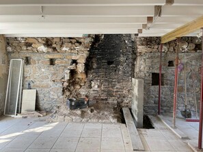 Exposed stone walls and a partially open ceiling frame this room, featuring a tiled floor and a doorway leading to another area.