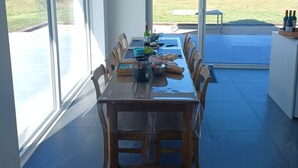 Un comedor con una mesa larga, sillas y vistas al exterior.