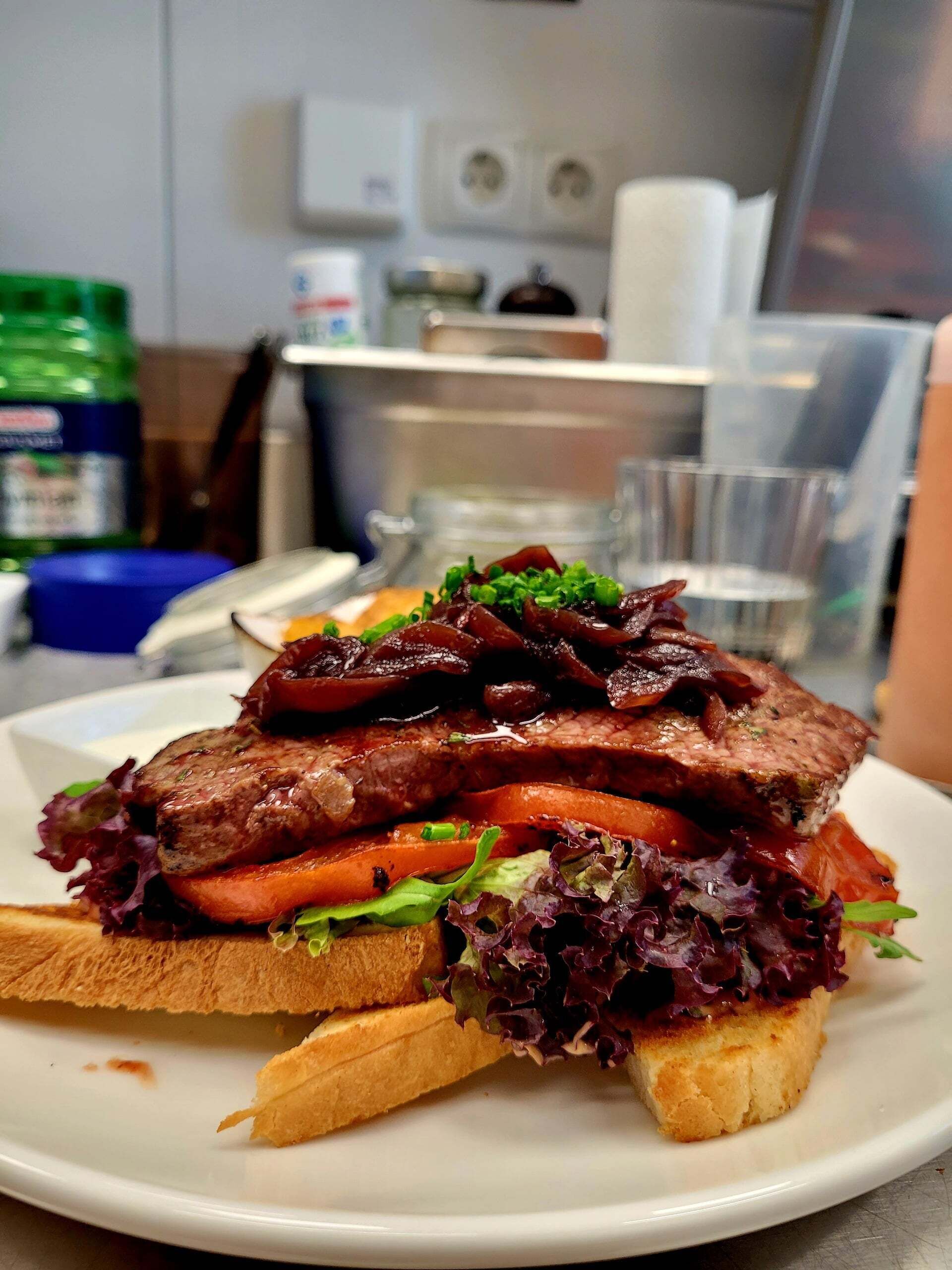 Sándwich de carne y verduras acompañado de papas fritas en un plato.