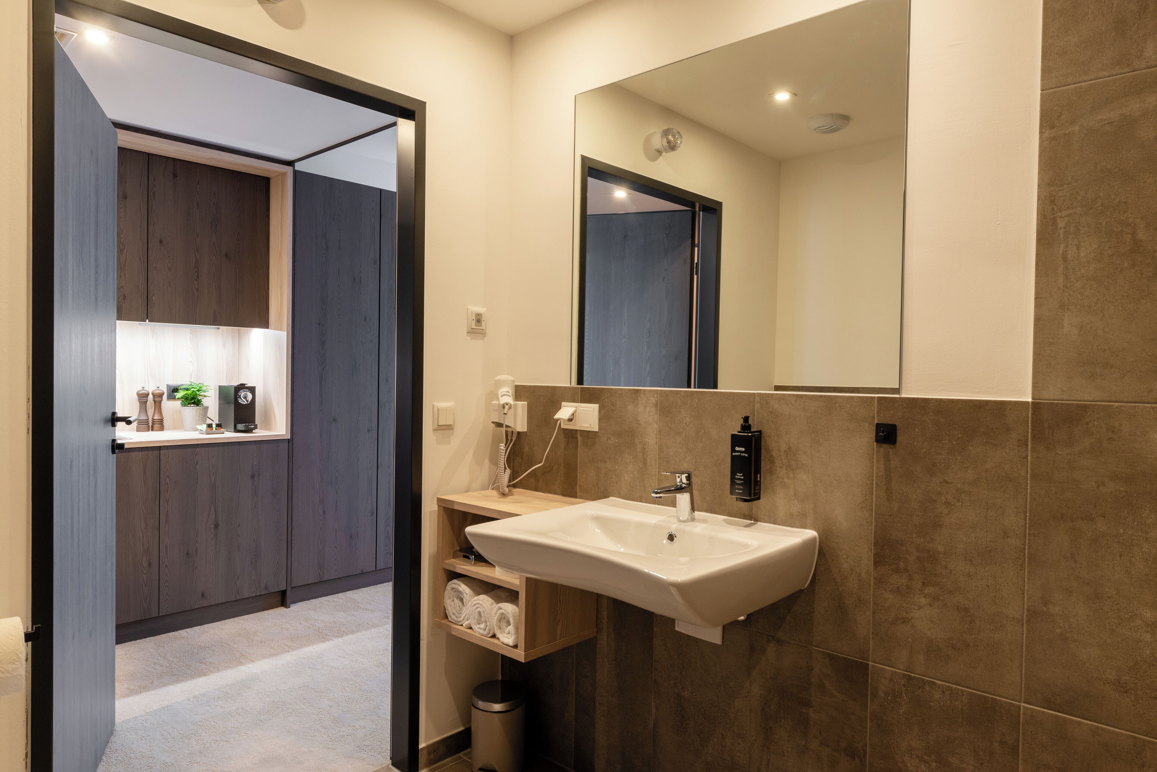 A modern bathroom with a large mirror, a sink, and a wooden vanity.