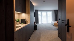 A modern hotel room with a kitchenette, a bed, and a large window with curtains. - Hotel Novapart (Wels)