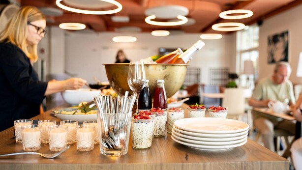 A buffet setup with various food items and drinks, including a large bowl, glasses, and plates. - Hotel Novapart (Wels)