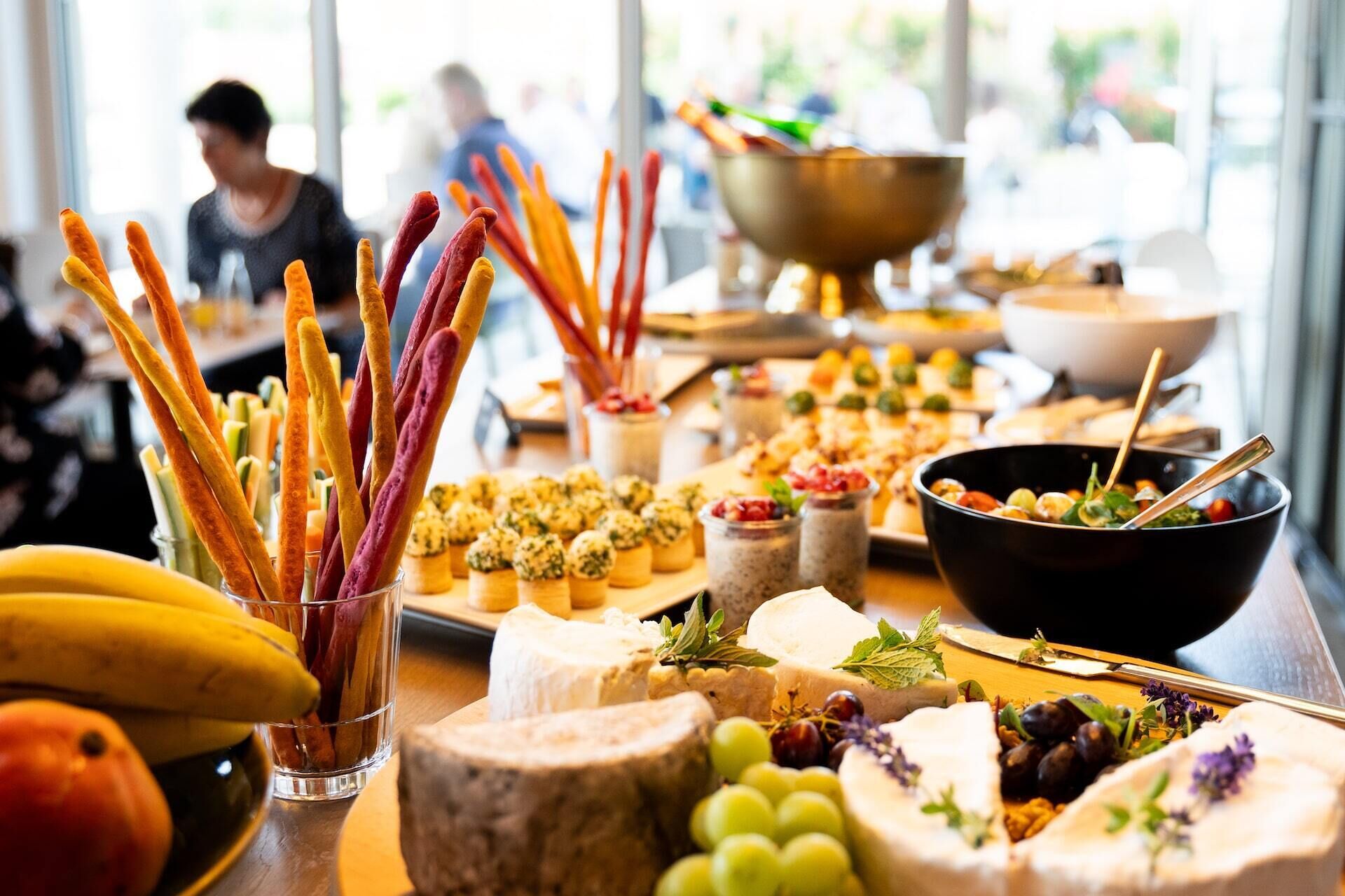 Una mesa de buffet con varios quesos, frutas y aperitivos.