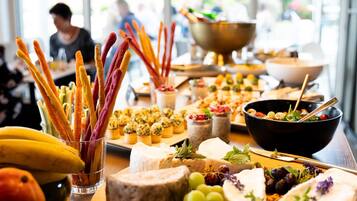 Una mesa de buffet con varios quesos, frutas y aperitivos.