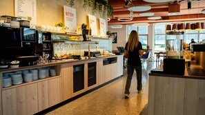 A modern cafe with a wooden counter, coffee machines, and a variety of food items.
