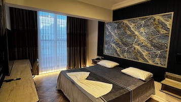 Un dormitorio moderno con una cama grande, un escritorio y un cuadro abstracto de grandes dimensiones en la pared.
