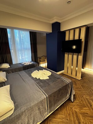 A hotel room with two beds, a flat-screen TV, and a wooden floor. - Hotel Bulut (Erzincan)