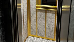 An elevator interior with a metallic finish, a control panel with a digital display, and a sign indicating a maximum weight limit. - Hotel Bulut (Erzincan)