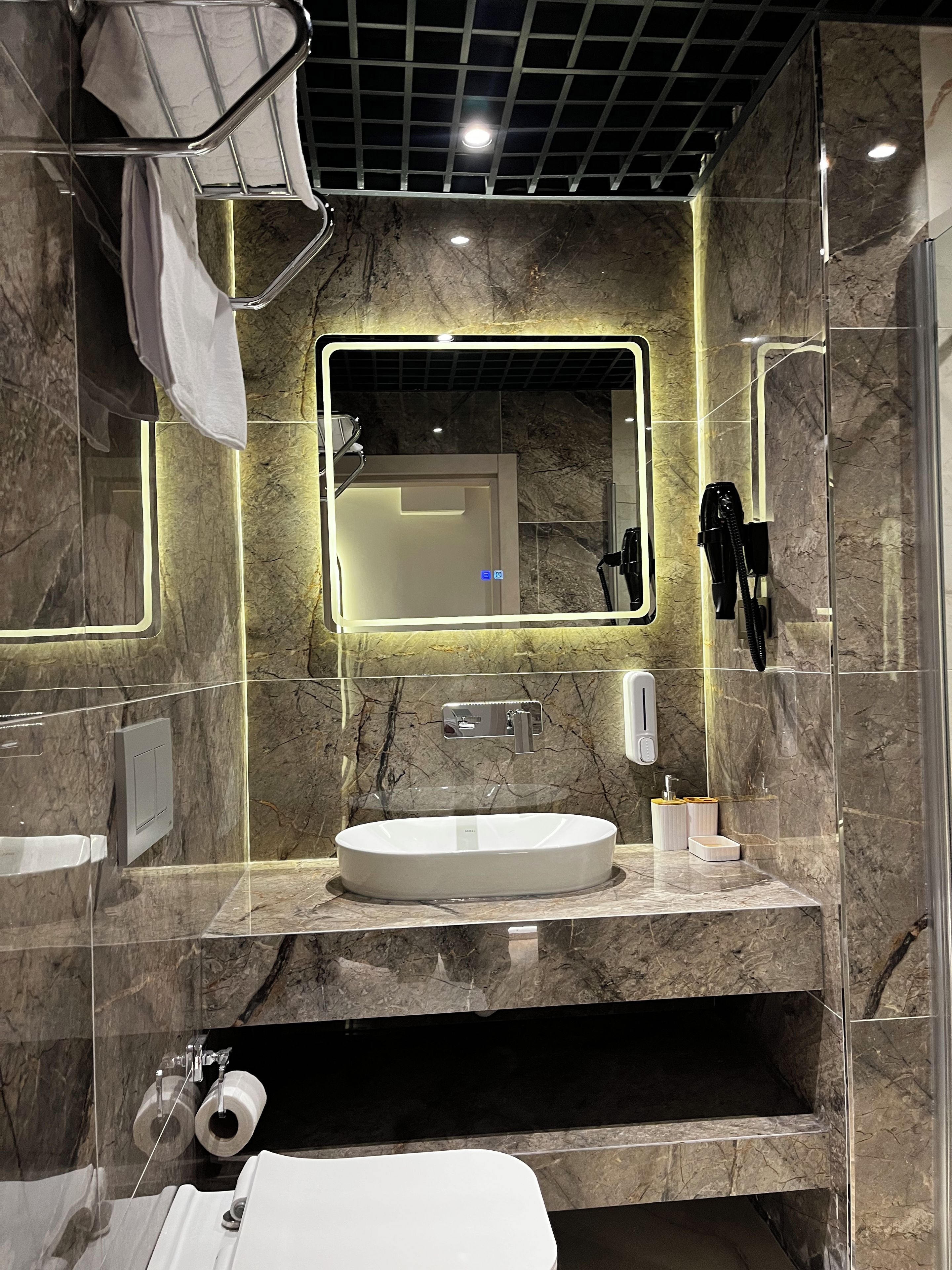 A modern bathroom with a large mirror, a sink, and a shower area.