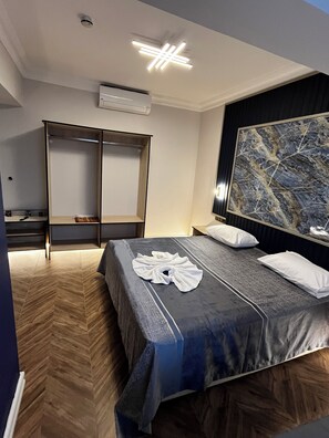 A hotel room with a bed, a wardrobe, a nightstand, and a large abstract painting on the wall. - Hotel Bulut (Erzincan)