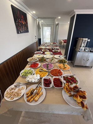 A buffet table with various dishes and a kitchen area in the background. - Hotel Bulut (Erzincan)