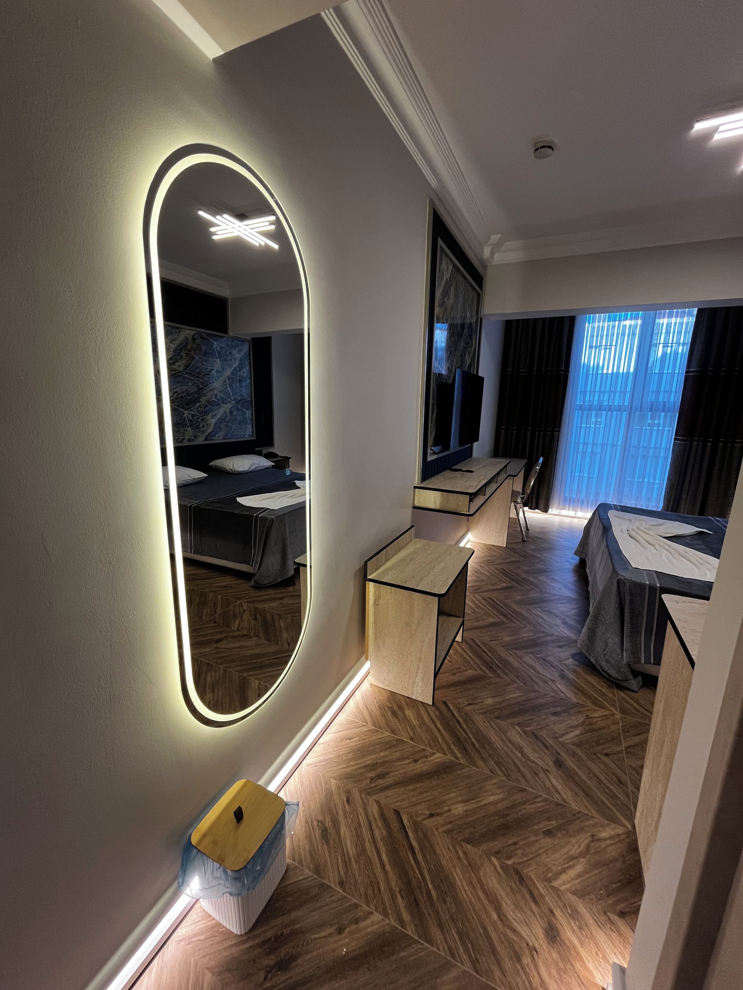 Ein Hotelzimmer mit großem Spiegel, einem Bett, einem Schreibtisch und einem Fernseher.