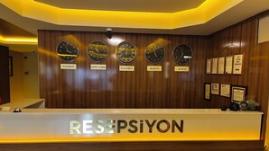 A reception desk with clocks displaying times from London, New York, Istanbul, Berlin, and Dubai. - Hotel Bulut (Erzincan)