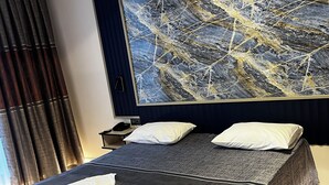 A hotel room with a large bed, a nightstand, a lamp, and a painting on the wall. - Hotel Bulut (Erzincan)
