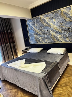 A hotel room with a large bed, a nightstand, a lamp, and a painting on the wall. - Hotel Bulut (Erzincan)