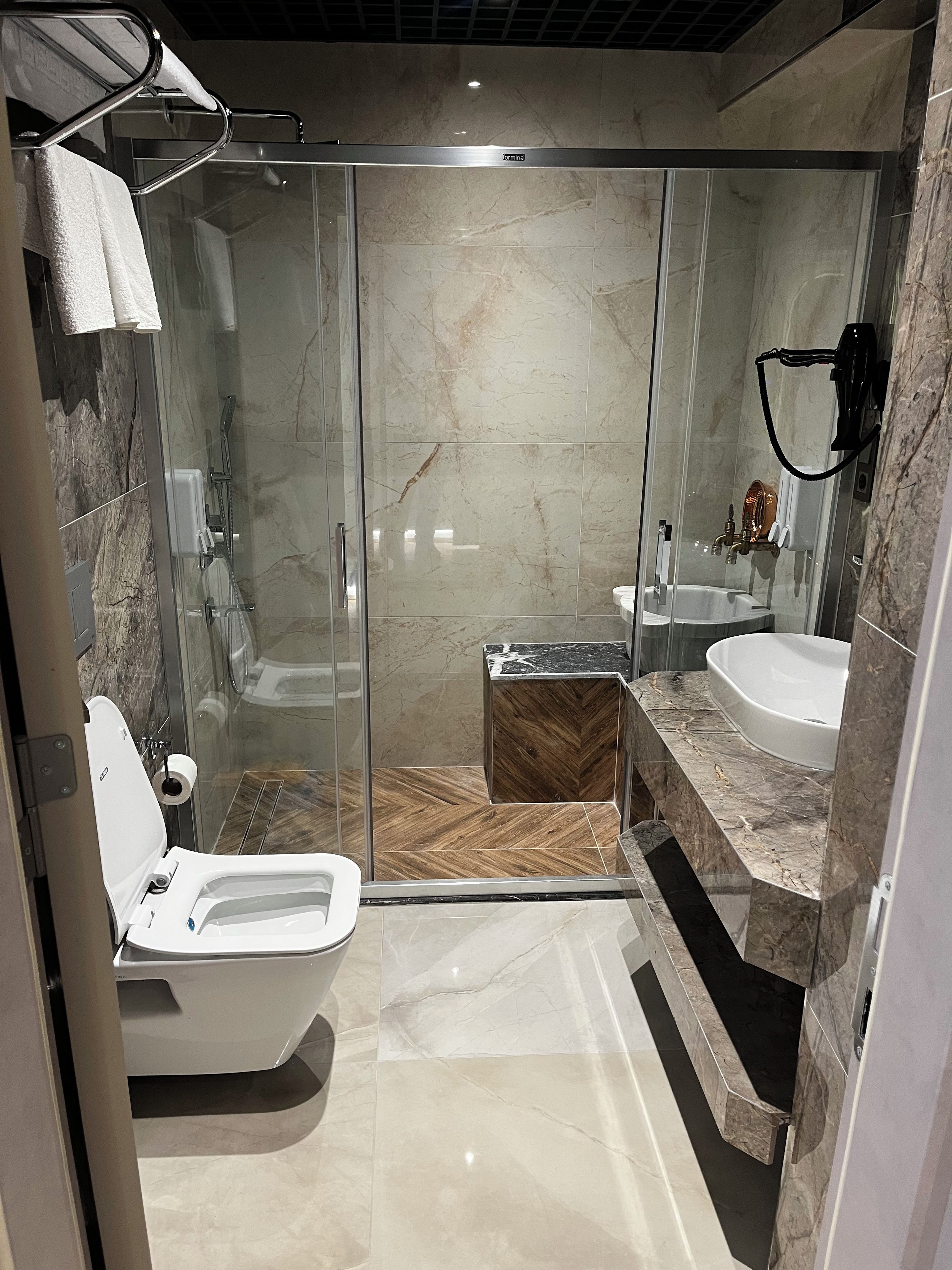 A modern bathroom with a glass-enclosed shower, a standalone toilet, and a vanity with a sink.