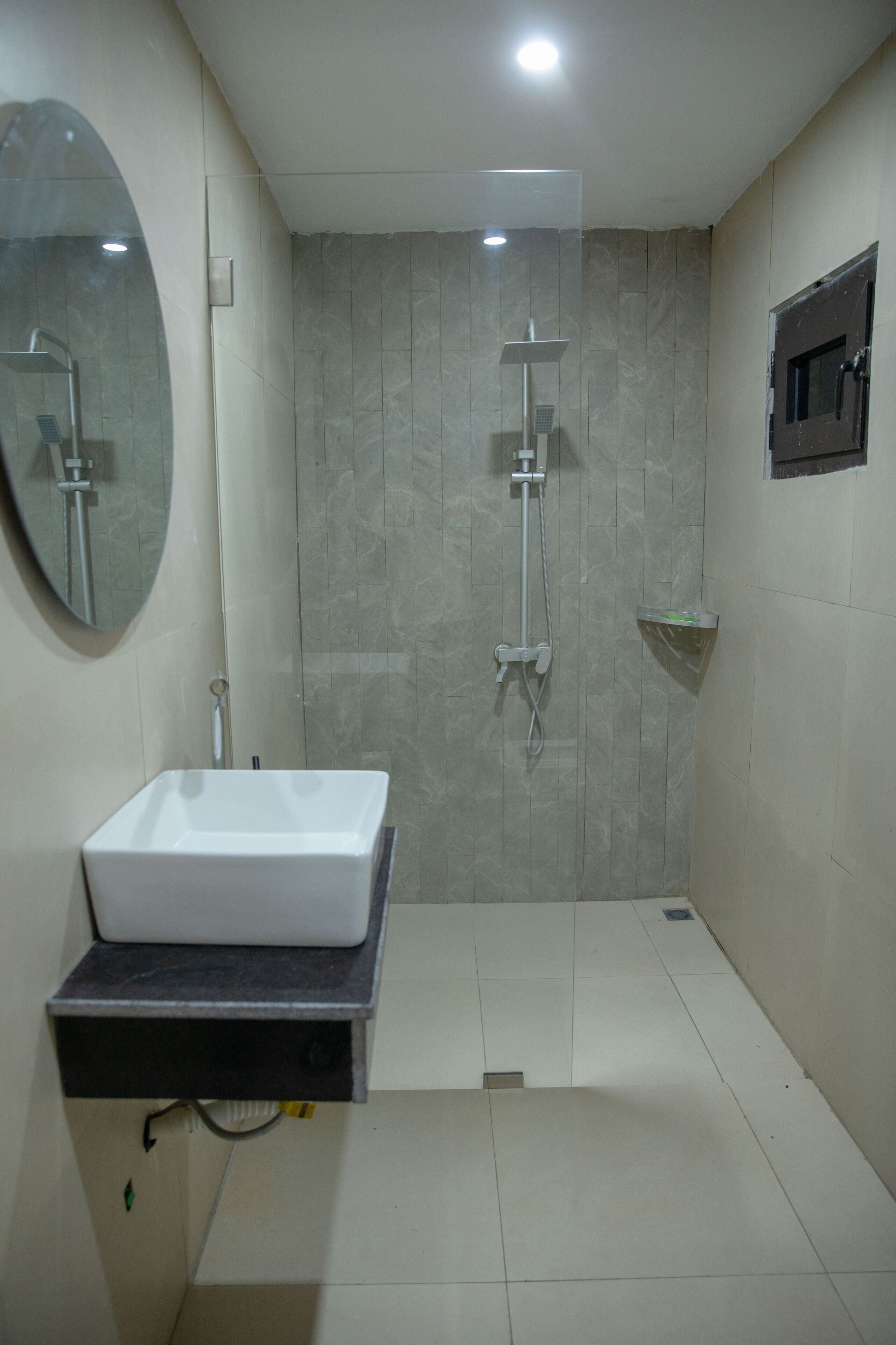A bathroom with a white sink, a shower with a handheld showerhead, and a mirror on the wall.
