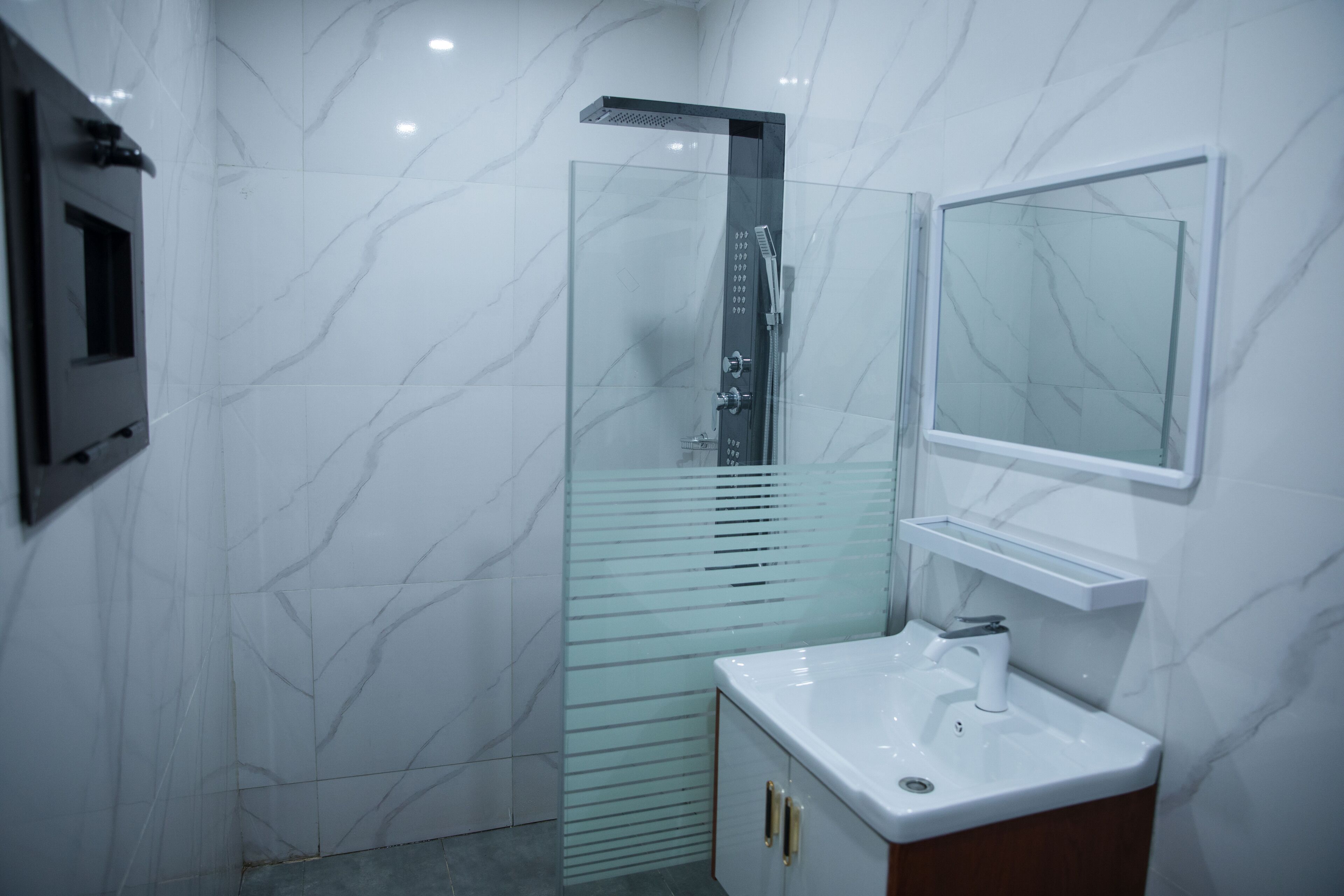 A modern bathroom with a glass shower enclosure, a white sink, and a mirror above it.