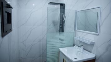 A modern bathroom with a glass shower enclosure, a white sink, and a mirror above it.