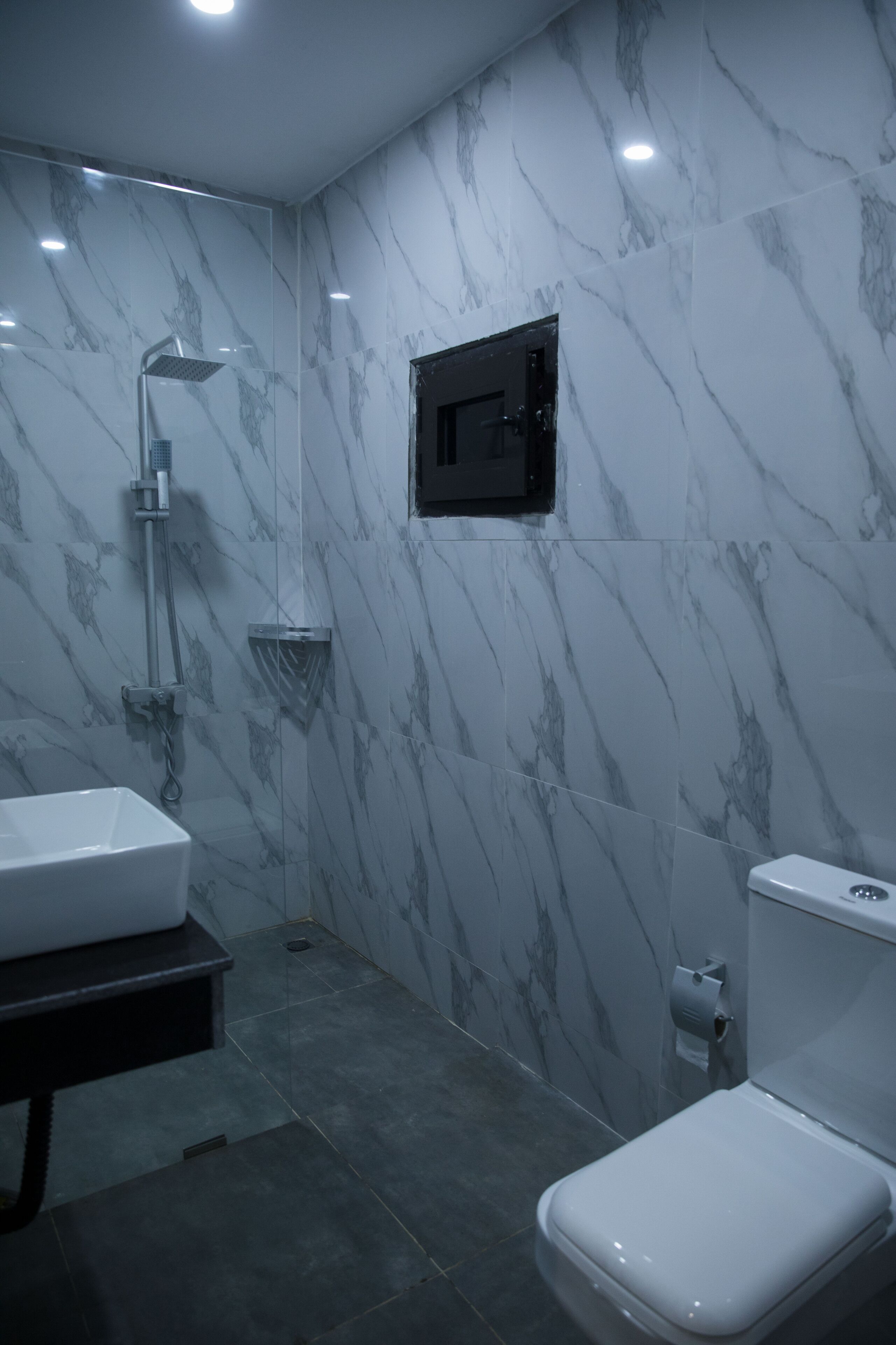 Un baño con lavamanos, inodoro y ducha blancos.