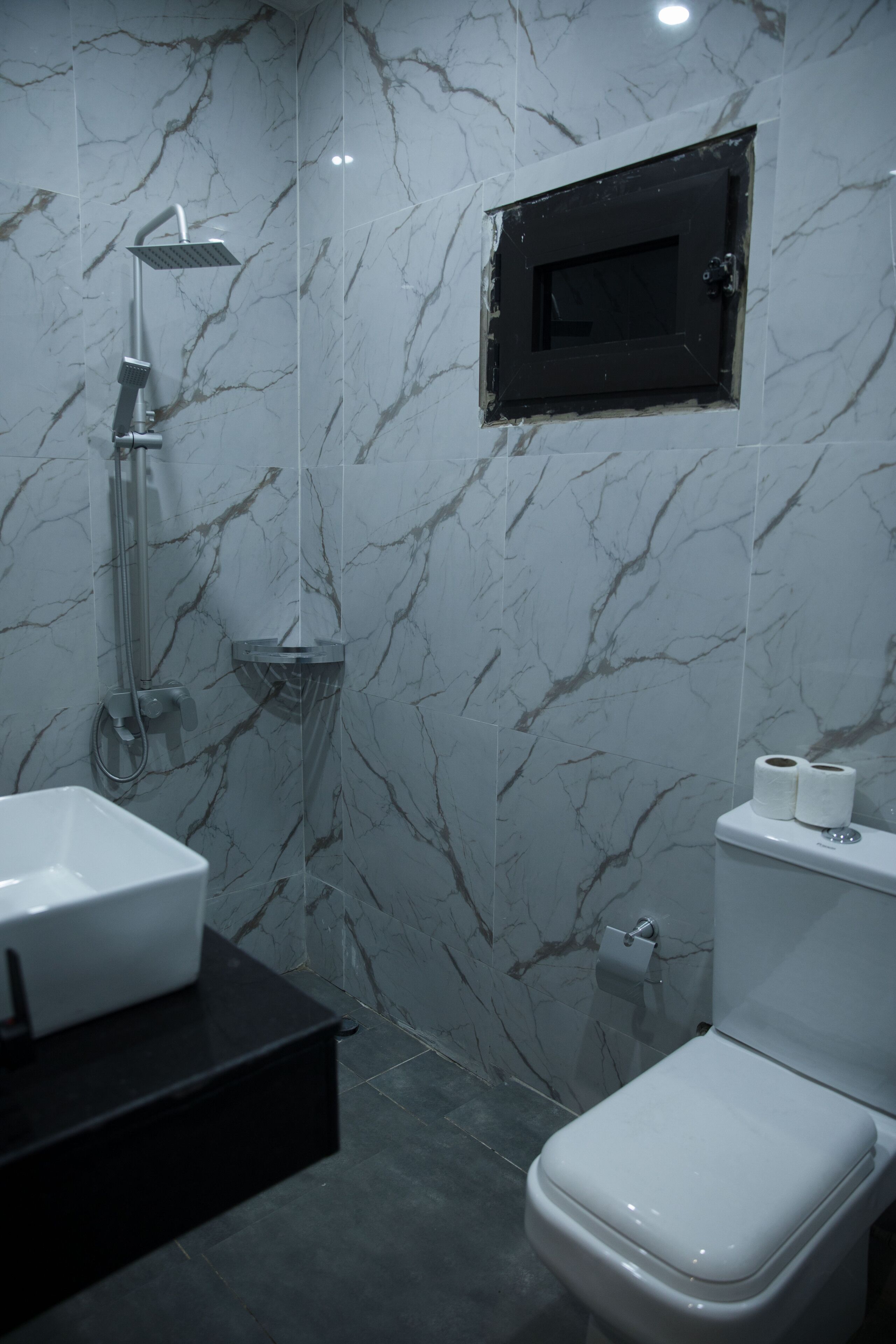 Een moderne badkamer met een wit wastafel, toilet en douche.