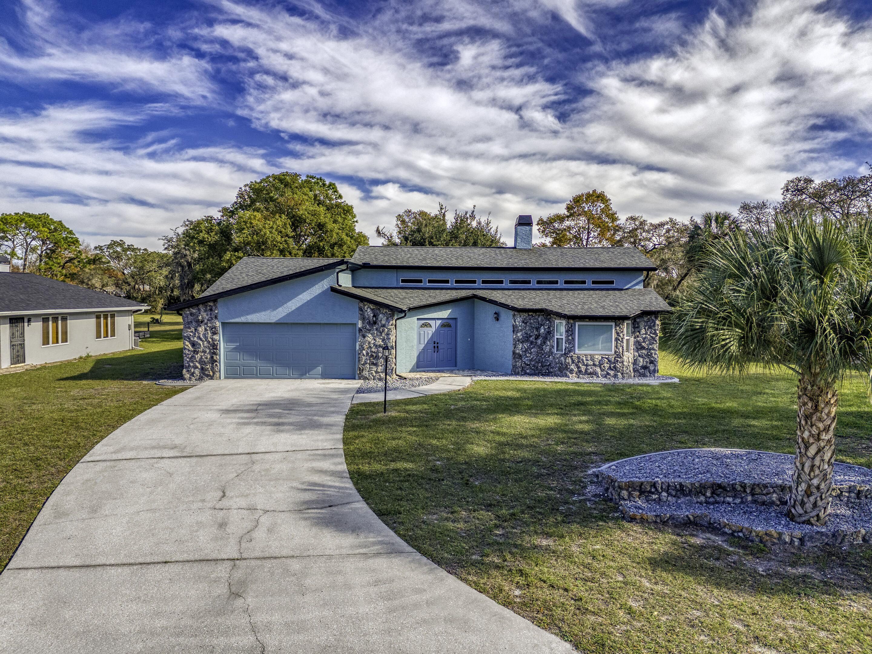 A two-story house with a stone facade, a garage, and a well-maintained lawn.