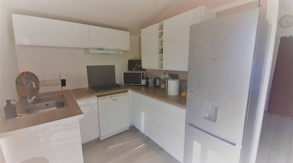 A kitchen with white cabinets, a microwave, a refrigerator, and a sink.