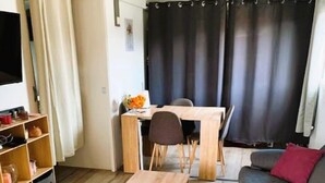 Ein gemütlicher Wohnraum mit Esstisch aus Holz, einer Couch und einem Fernseher.