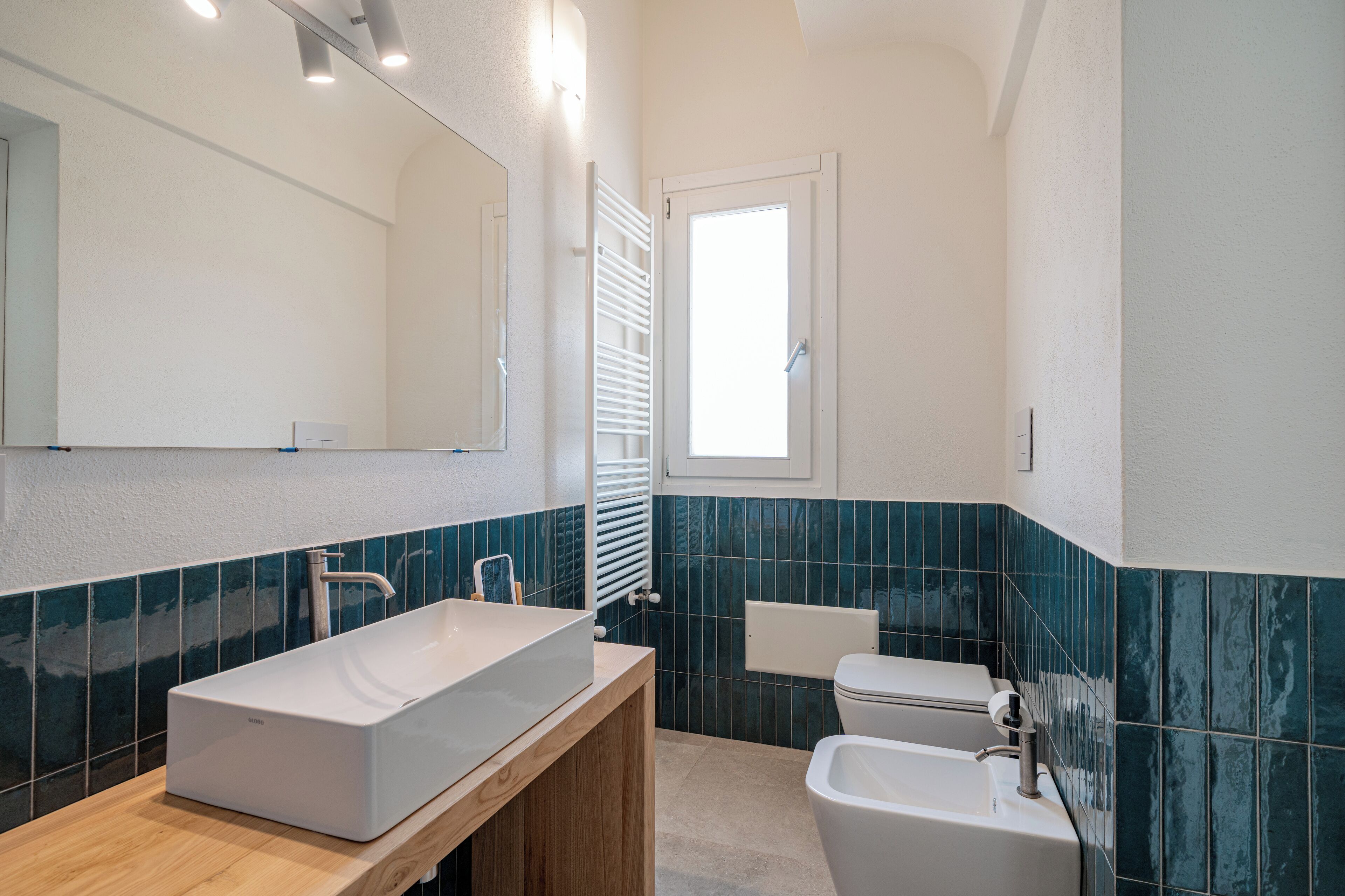 A modern bathroom with a large rectangular sink, a toilet, and a bidet.