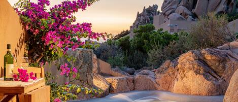Ein friedliches Außenpool-Areal mit natürlichen Felsformationen und blühenden Bougainvilleen.