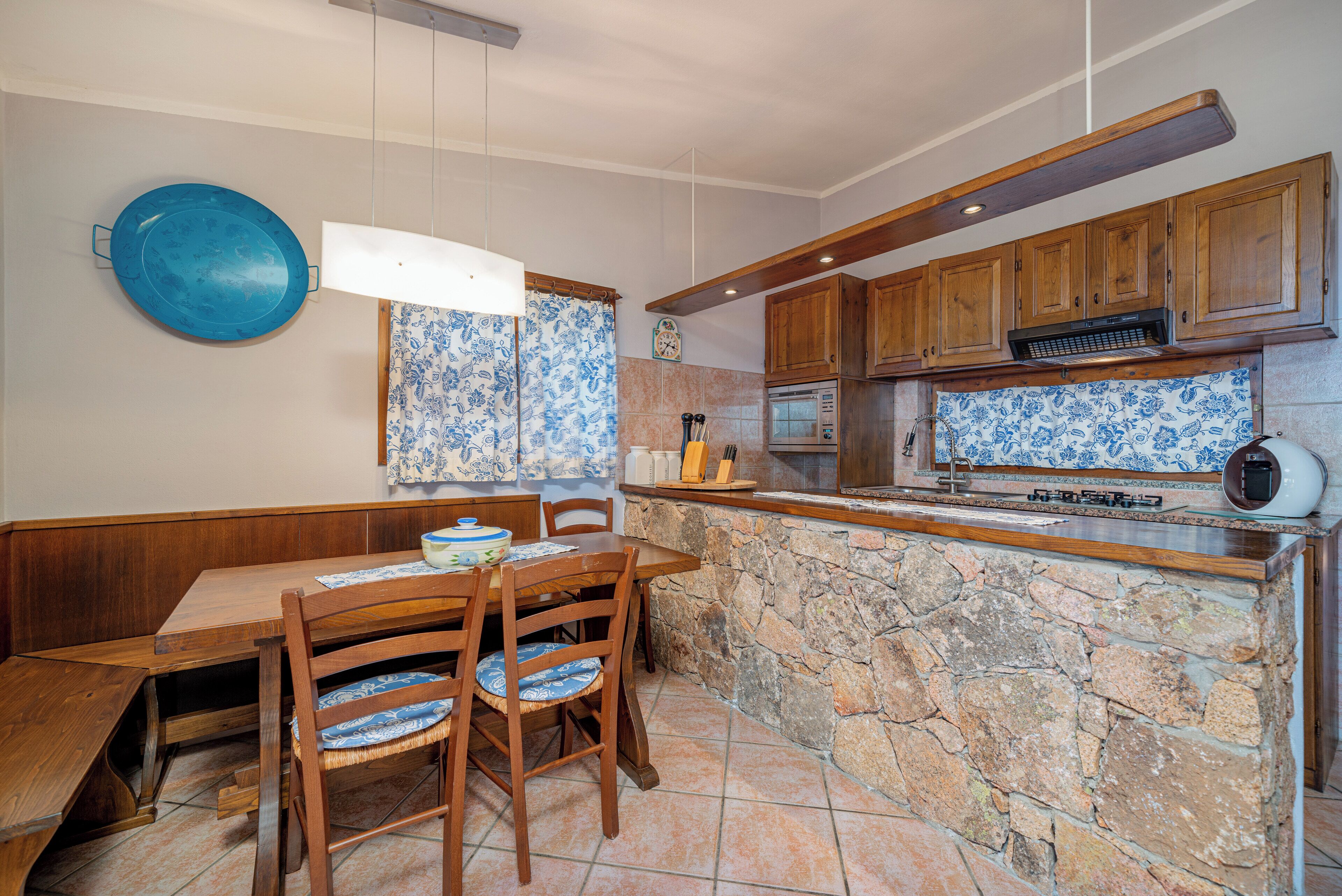 A kitchen with wooden cabinets, a stone countertop, and a dining area with a table and chairs.