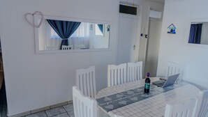 Een eetruimte met een tafel, stoelen, een laptop en een fles.
