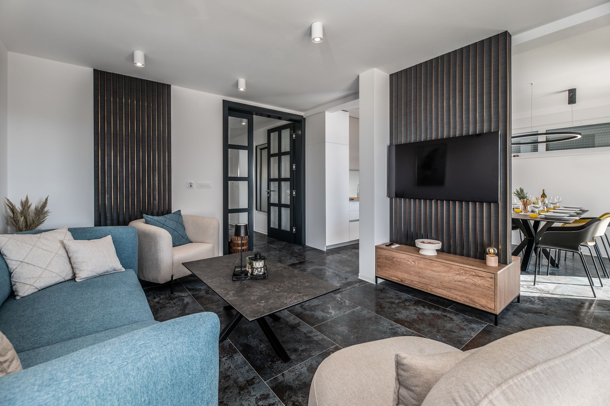 A modern living room with a sofa, coffee table, and a TV mounted on the wall.