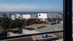 A balcony with a view of a residential area, a parking lot, and a clear sky.