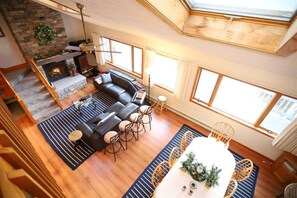 Ein geräumiges Wohnzimmer mit Kamin, einem Essbereich und einer Treppe, die in eine obere Etage führt.