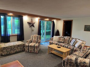 Ein Wohnzimmer mit einer Couchgarnitur, einem Sessel, einem Couchtisch und einem Haustierbett.